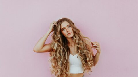 woman standing next to pink wall while scratching her head