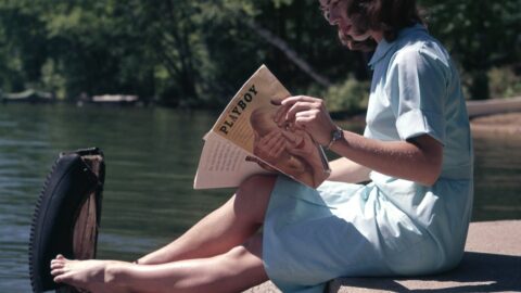 woman sitting while reading near body of water